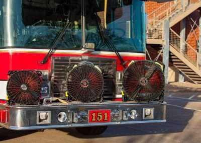 Three BlowHard fans sit on the front bumper of a firetruck, showcasing the size comparison of each model.